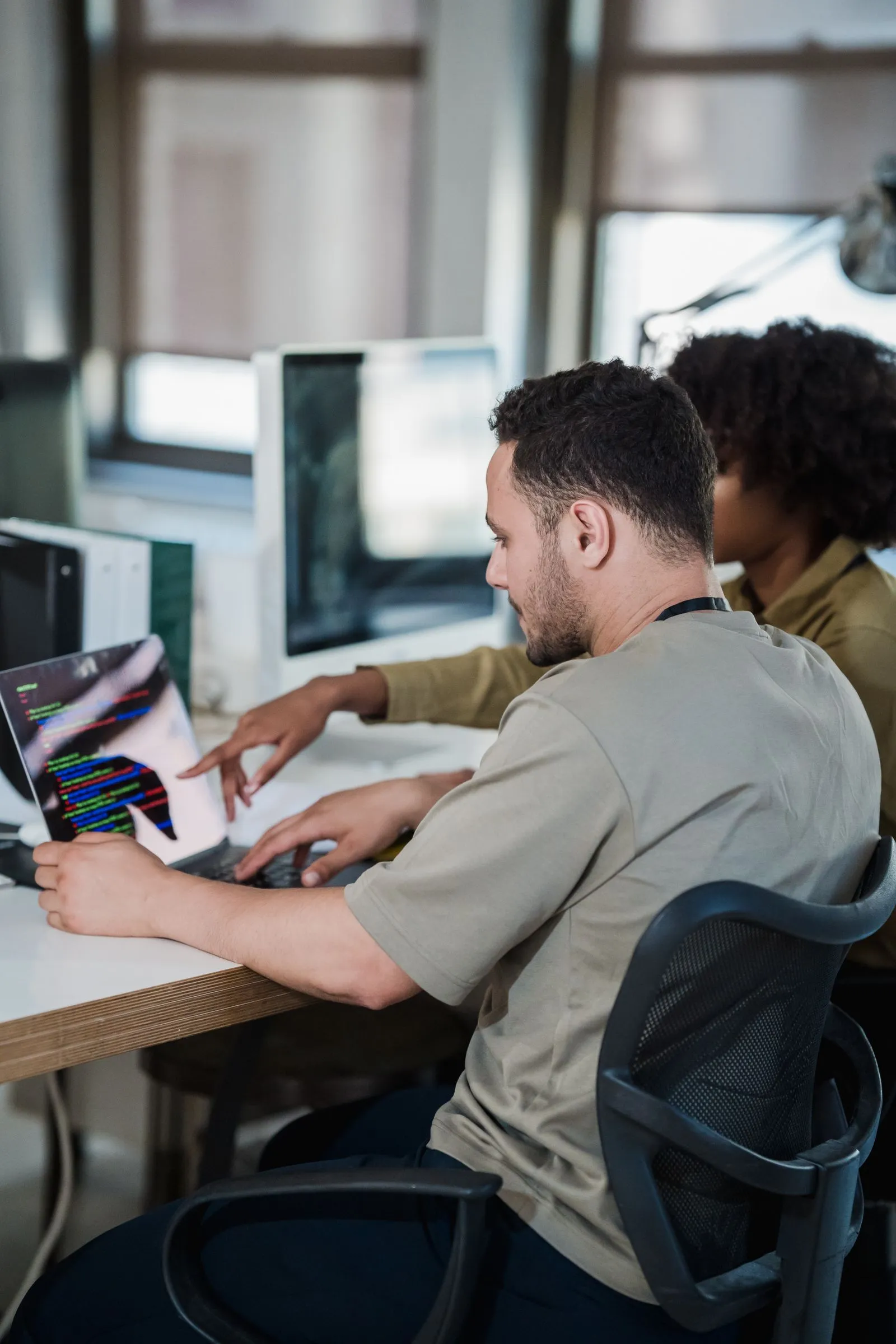 Two CodeCrew engineers pair-programming at a workstation.